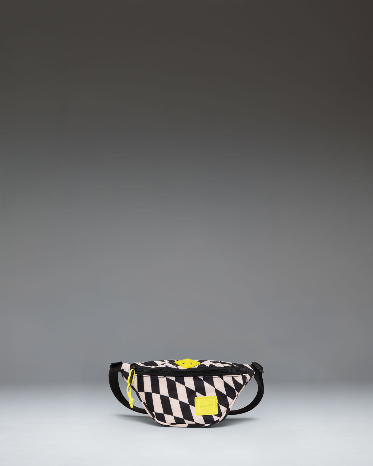 Herschel Heritage Hip Pack Little Herschel in Warp Check, a black and white checkered kids fanny pack with a brown rubber diamond accent.