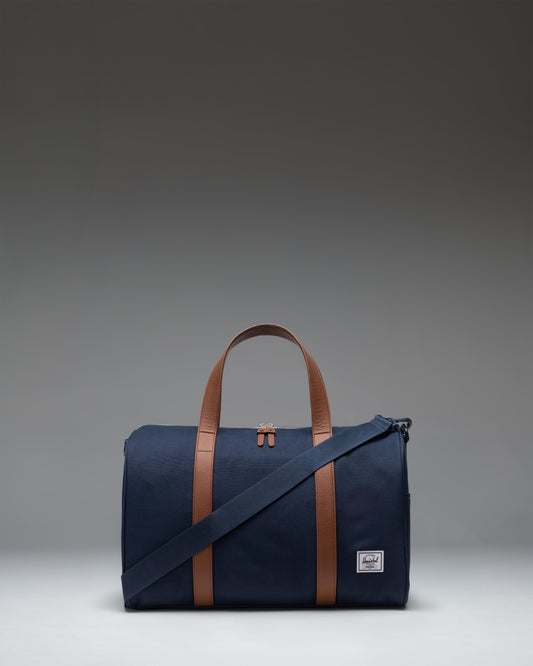 Herschel Novel Carry On Duffle in navy blue featuring a signature shoe compartment, top handles, and a removable shoulder strap.