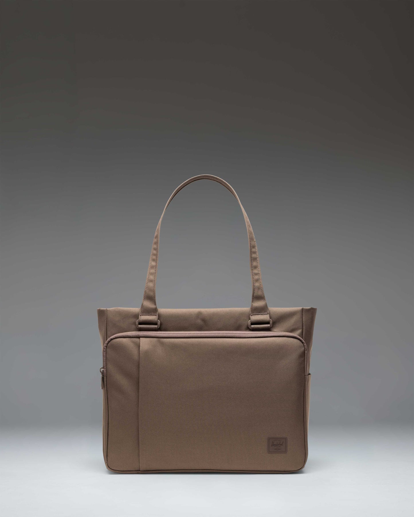 Herschel Supply Co. Kaslo Tote Tech bag in light brown, showing a front view with its durable handles and sleek, minimalist design.
