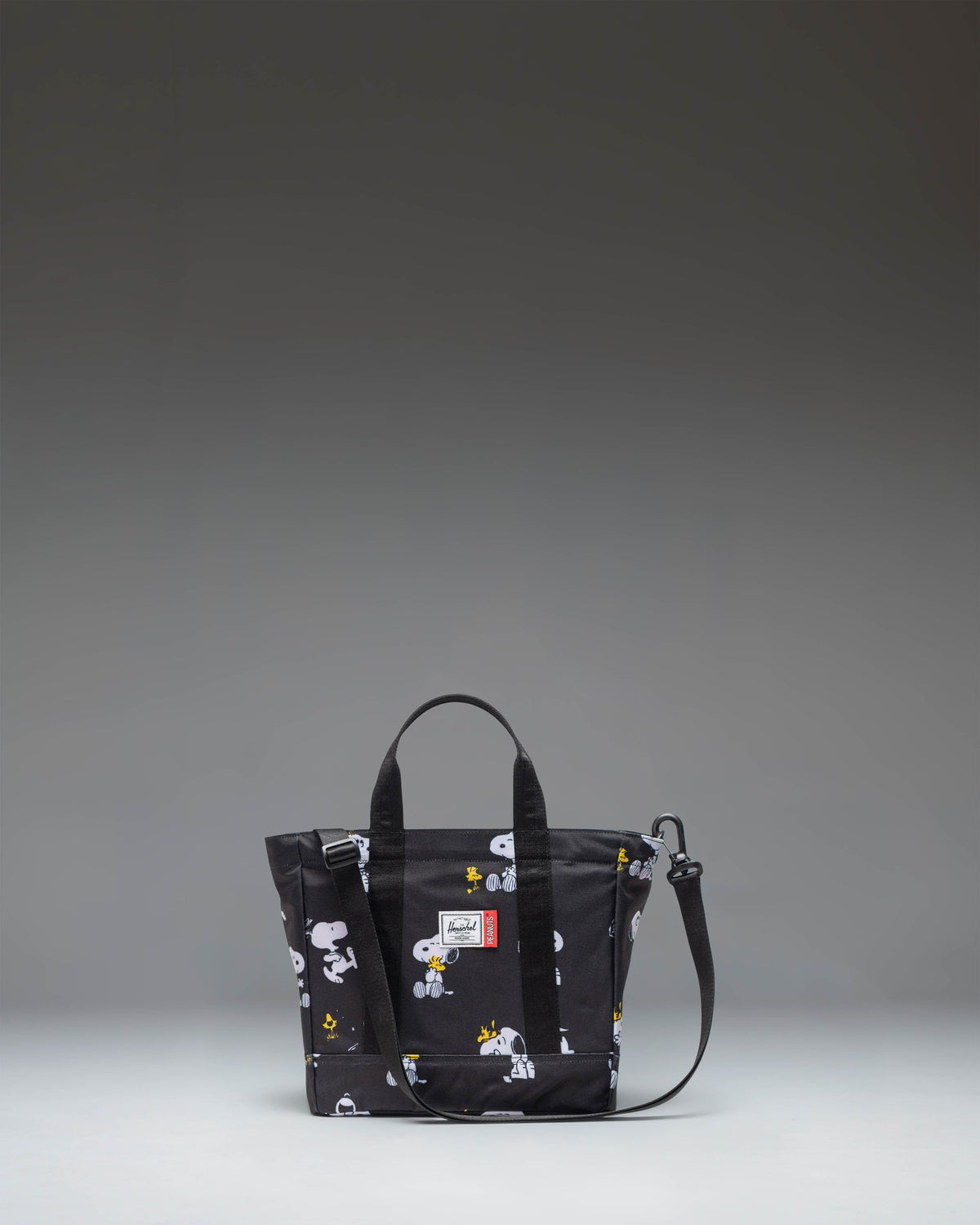 Black Peanuts Herschel Heritage Small Tote bag featuring a Snoopy and Woodstock graphic print on the front pocket.
