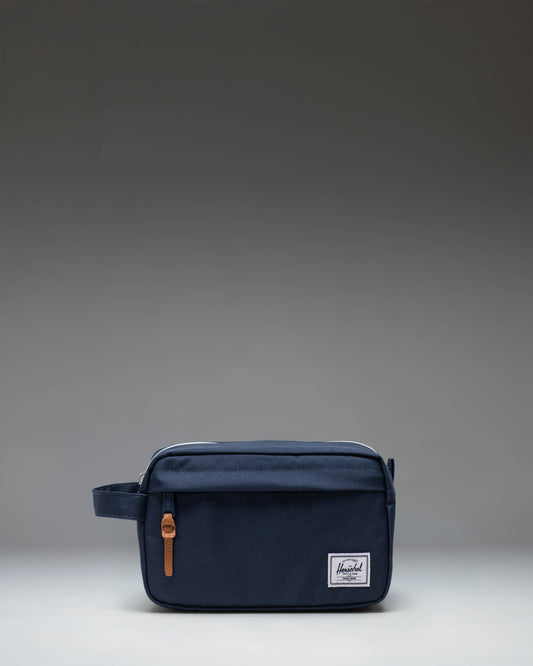 Herschel Supply Co. Chapter Travel Kit in navy blue, showing a side view of the structured travel pouch with a carrying handle.