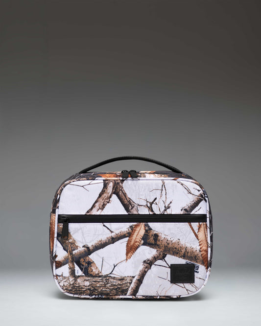 Herschel Supply Co. Realtree Pop Quiz Lunch Box in Realtree Edge Camo White/Black, showing the insulated interior and front zippered pocket.