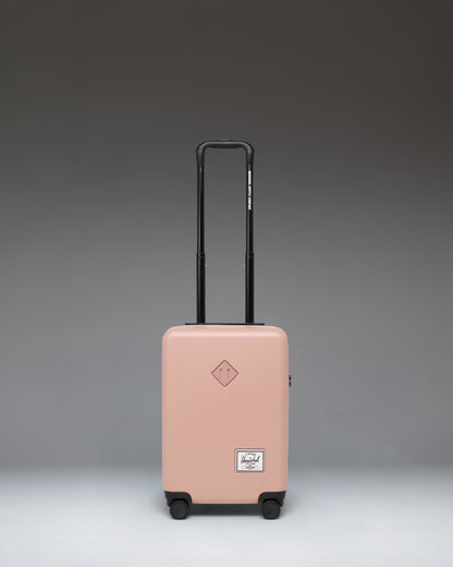 Herschel Heritage Hardshell Carry On Luggage in Ash Rose. Front view of the durable hard shell suitcase with wheels and a retractable handle.