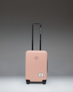 Herschel Heritage Hardshell Large Carry-On Luggage in Ash Rose pink, featuring a durable textured exterior, telescopic handle, and multi-directional wheels.