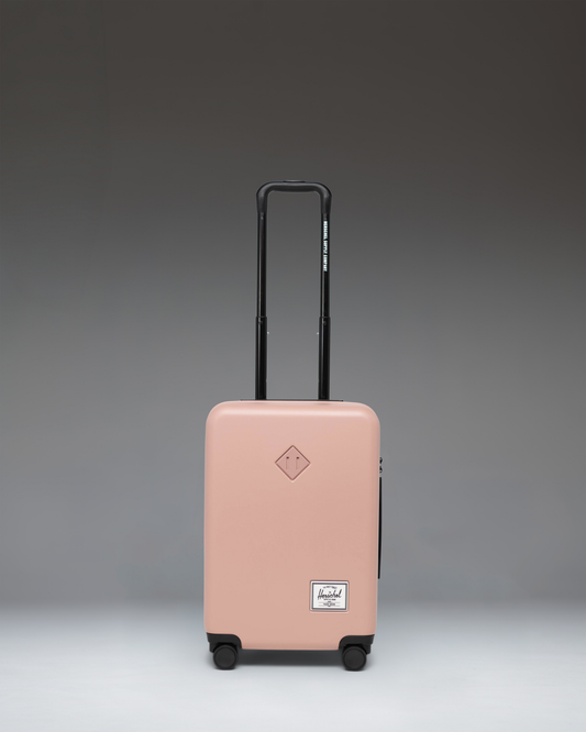 Herschel Heritage Hardshell Large Carry-On Luggage in Ash Rose pink, featuring a durable textured exterior, telescopic handle, and multi-directional wheels.