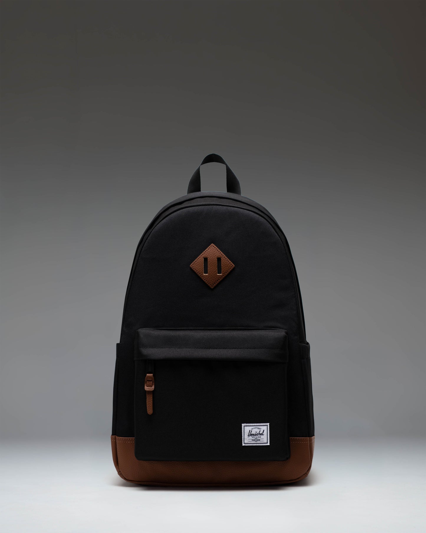 Herschel Heritage Backpack in Black with a Tan brown diamond accent and bottom panel, shown from the front on a white background.