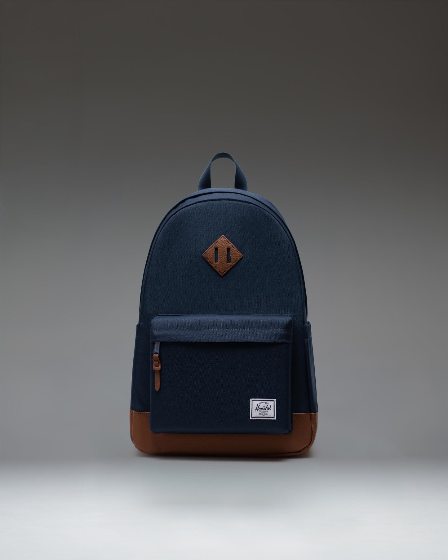 Herschel Supply Co. Heritage Backpack in Navy/Tan, front view showing the main zippered compartment and front pocket with a tan base.