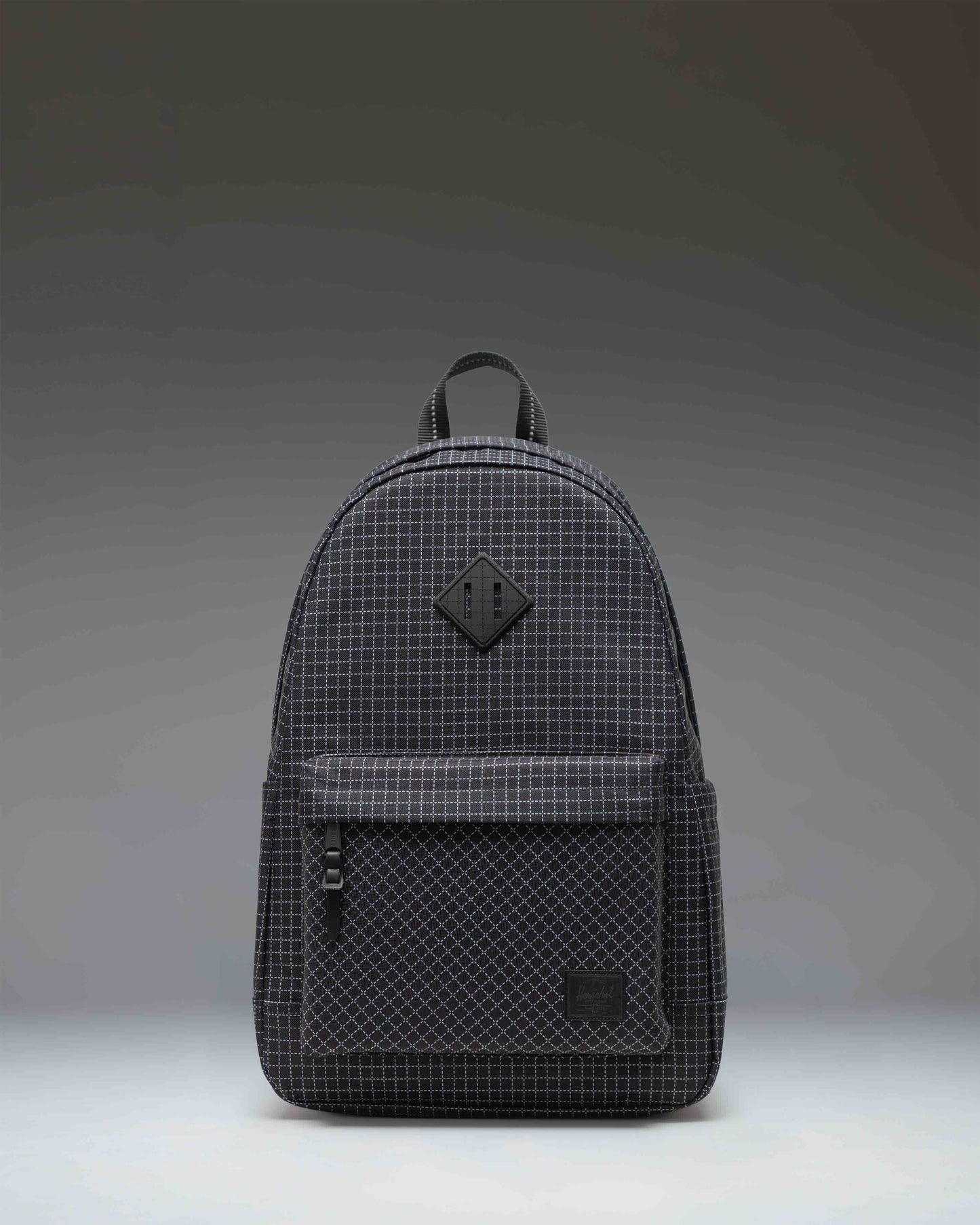 Herschel Heritage Backpack in Grid - Black, featuring a classic design with a front storage pocket and a rubber diamond accent.