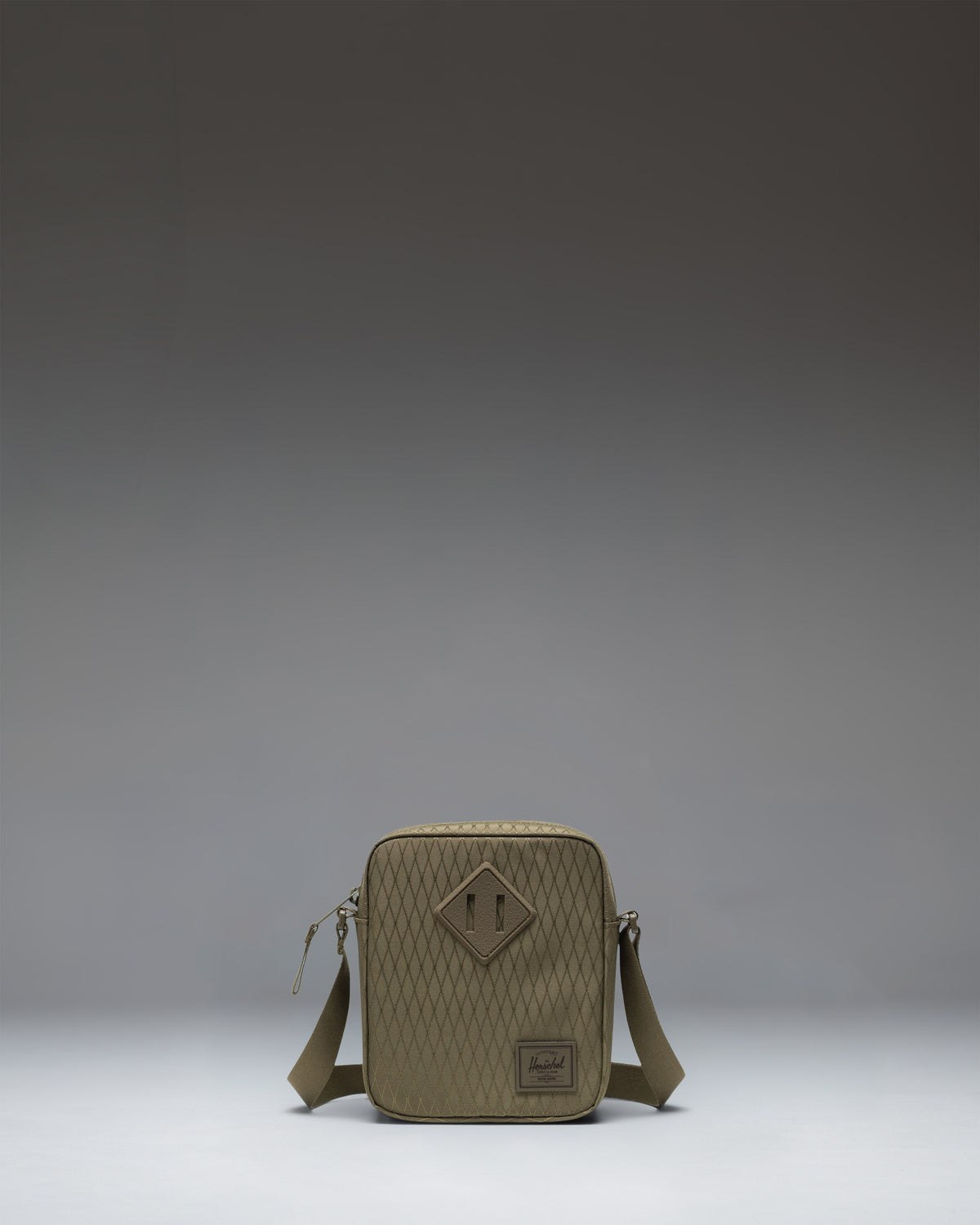Herschel Supply Co. Heritage Crossbody bag in Ivy Green Diamond, featuring a classic rectangular design with a front zippered pocket.