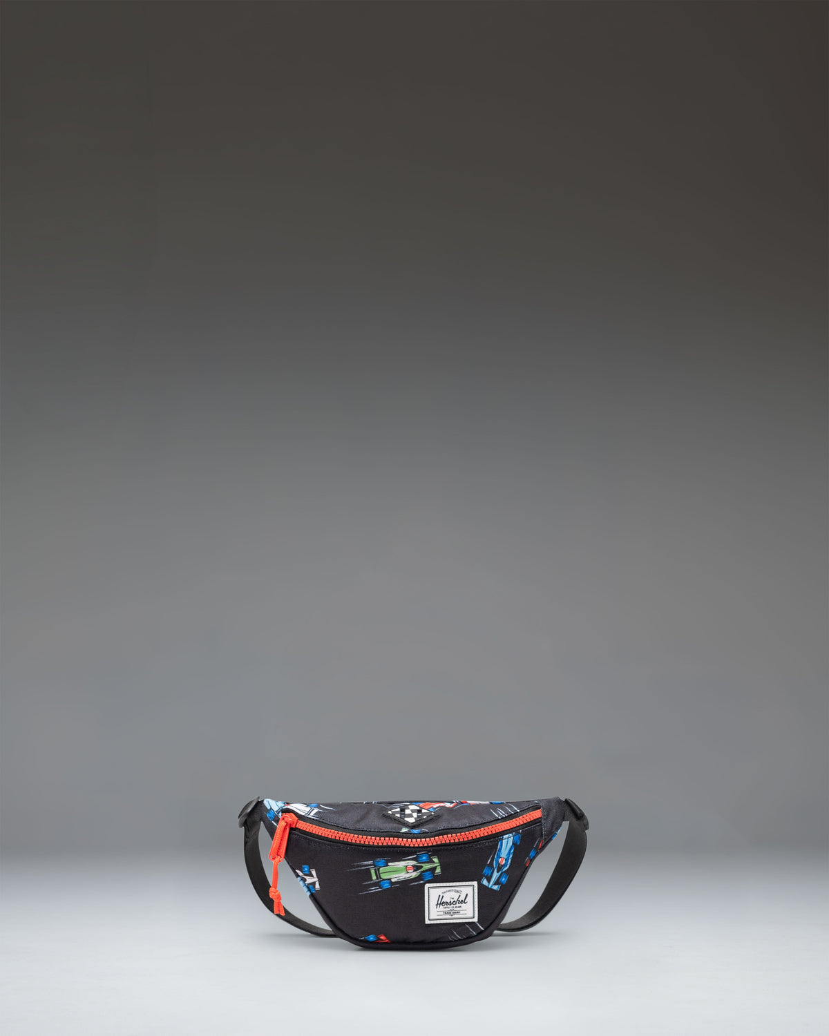 Little Herschel Heritage Hip Pack in Race Cars print featuring a red and blue race car pattern on a white background.