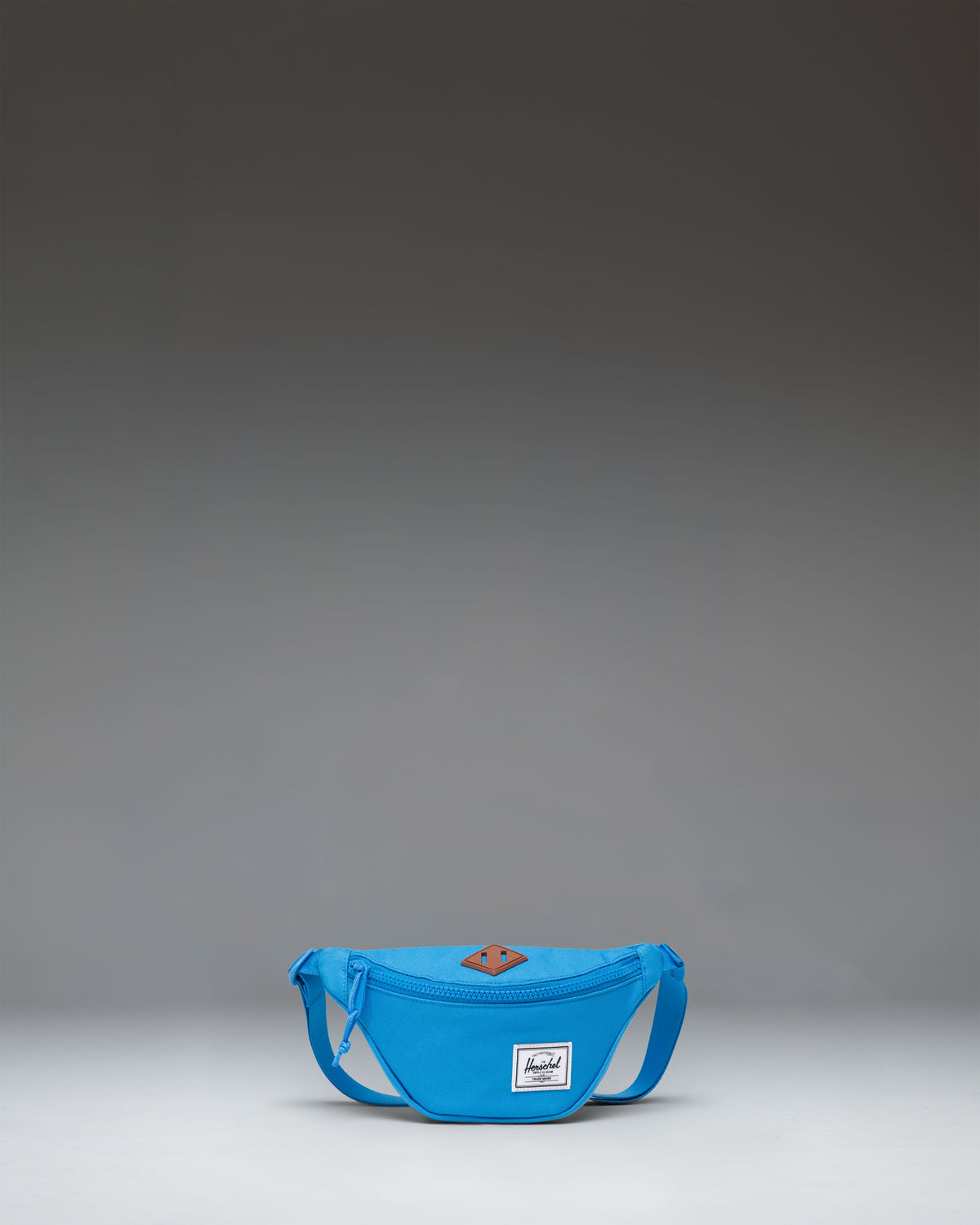 Herschel Heritage Hip Pack Little Herschel in French Blue, showing a compact hip pack with a front zippered pocket and adjustable strap.