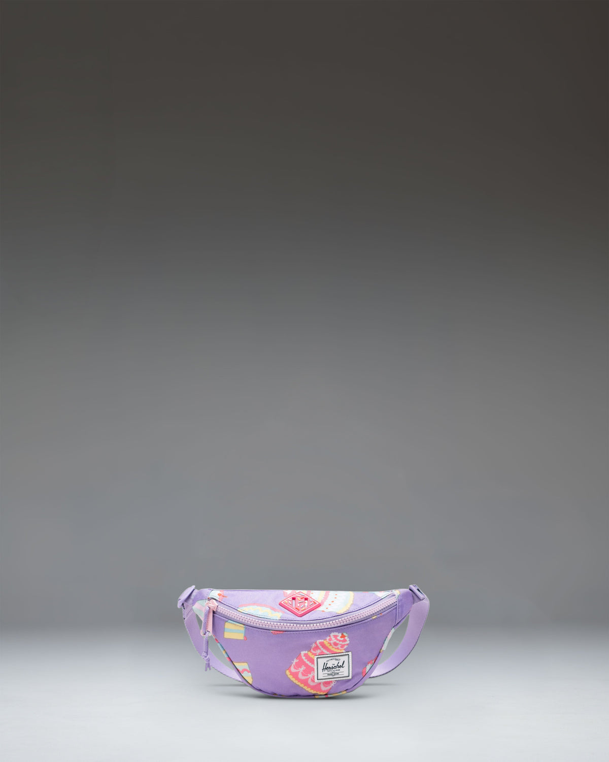 Herschel Heritage Hip Pack Little Herschel in Cakes colorway, featuring a whimsical pattern of birthday cakes, candles, and sprinkles.