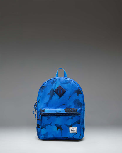Herschel Heritage Kids Backpack in Sharks pattern, featuring a blue background with various shark illustrations, front pocket, and shoulder straps.