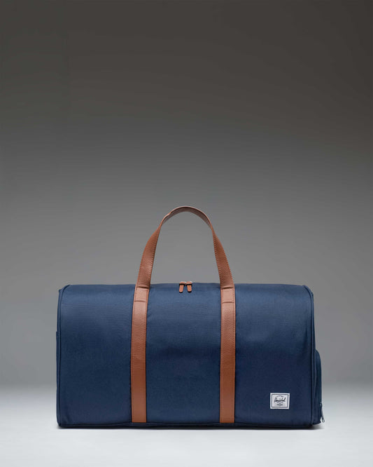 Navy blue Herschel Novel Duffle bag with two top carrying handles and a shoulder strap.
