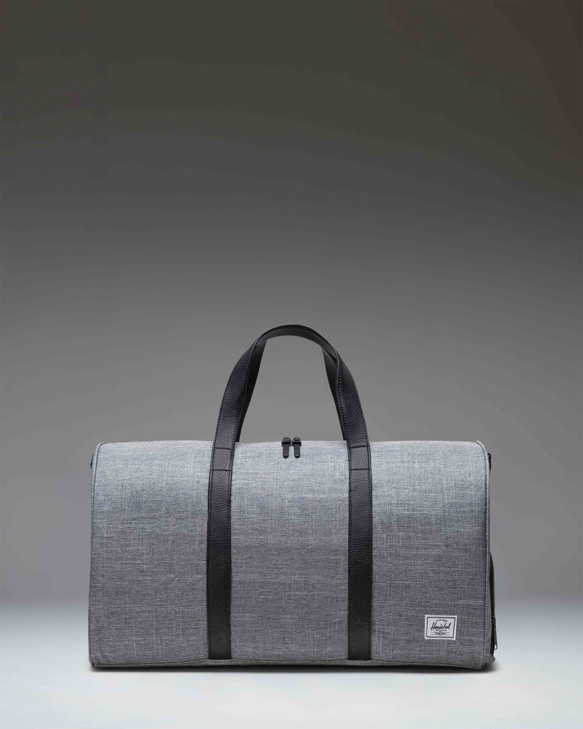 Herschel Novel Duffle bag in Raven Crosshatch grey with black carrying handles and a removable shoulder strap.