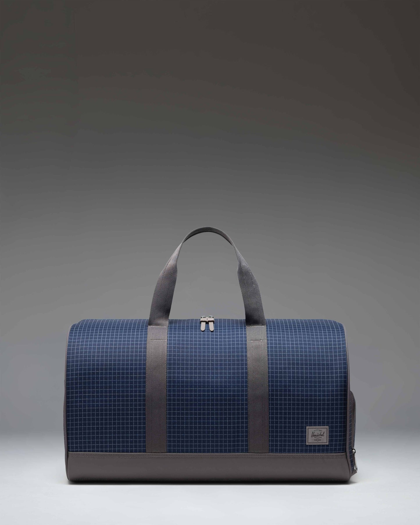 Herschel Supply Co. Novel Duffle bag in Grid Naval Academy/Magnet, a navy blue and gray checkered grid pattern.