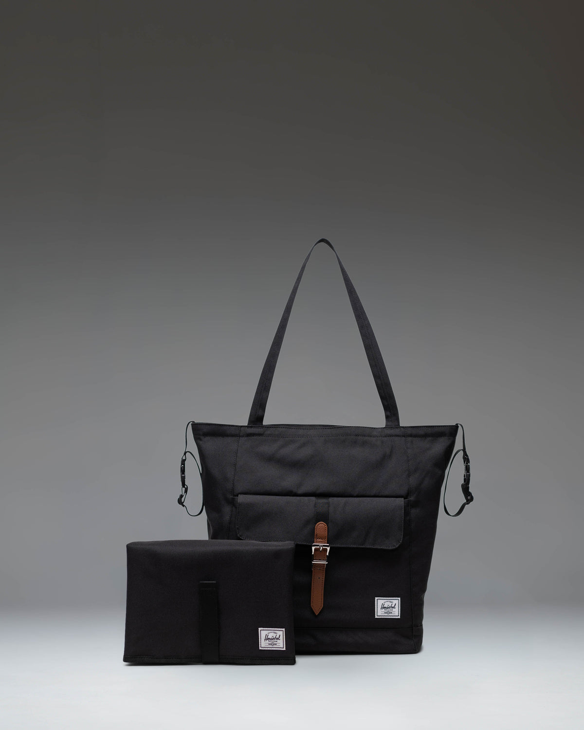 Black Herschel Retreat Tote Diaper Bag shown from the front, highlighting its clean design, shoulder straps, and iconic woven label.