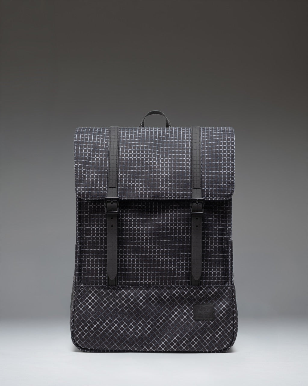 Herschel Survey Backpack in Grid - Black. Front view of the everyday backpack featuring dual magnetic strap closures.