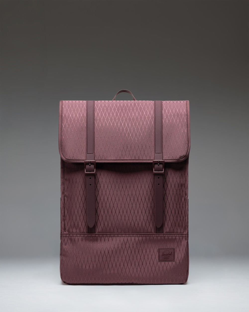 Herschel Survey Backpack in Huckleberry Diamond, a purple backpack with black rubber strap closures and a front storage sleeve.