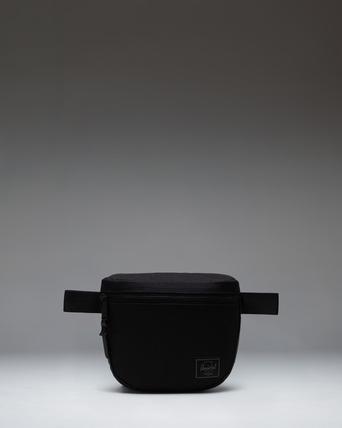 Herschel Supply Co. Settlement Hip Pack in Black Tonal, showing the classic pack design with a front zippered pocket and adjustable strap.