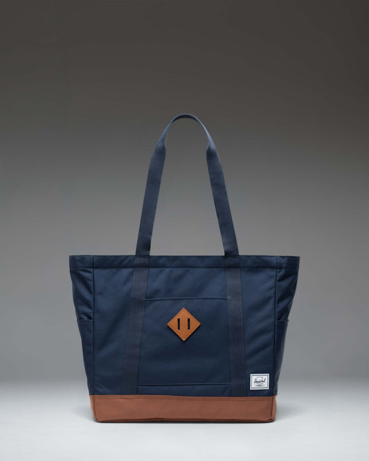 Herschel Heritage Tote in Navy blue with a Saddle Brown base and shoulder straps, shown from a front perspective.
