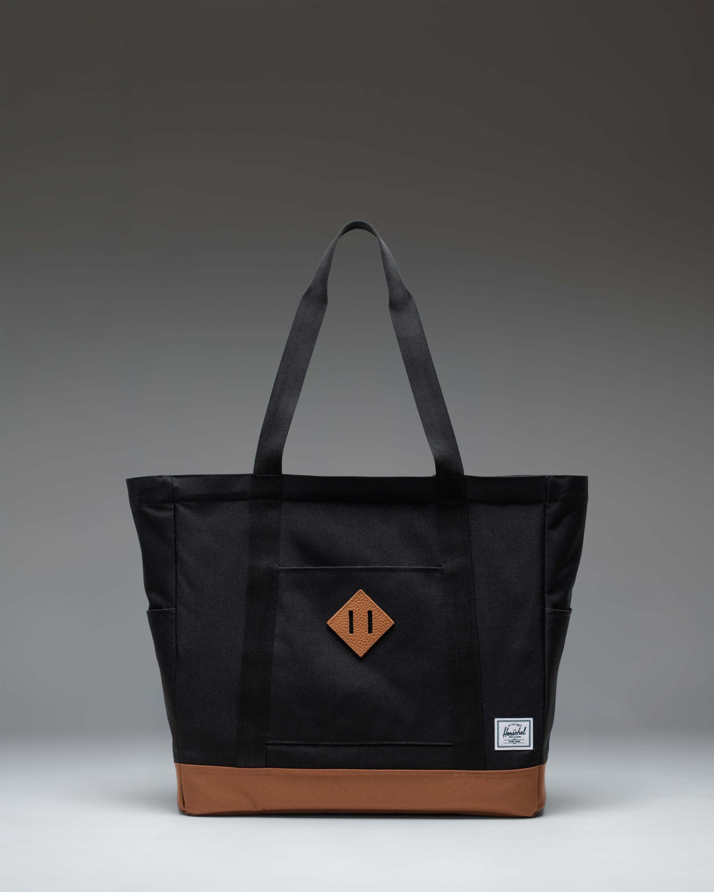 Herschel Heritage Tote bag in Black with Saddle Brown straps and base detailing, shown from the front against a plain background.