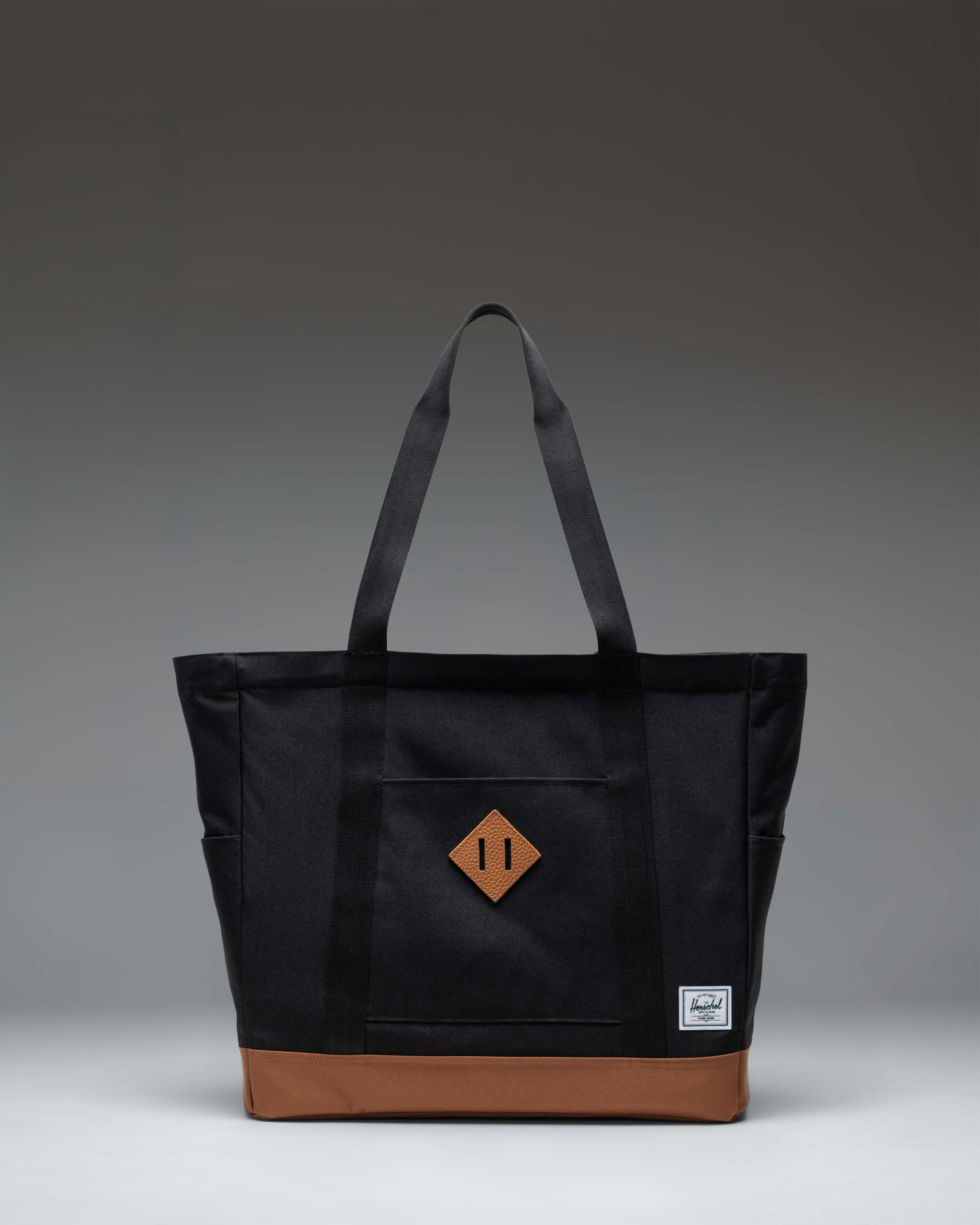 Herschel Heritage Tote bag in Black with Saddle Brown straps and base detailing, shown from the front against a plain background.