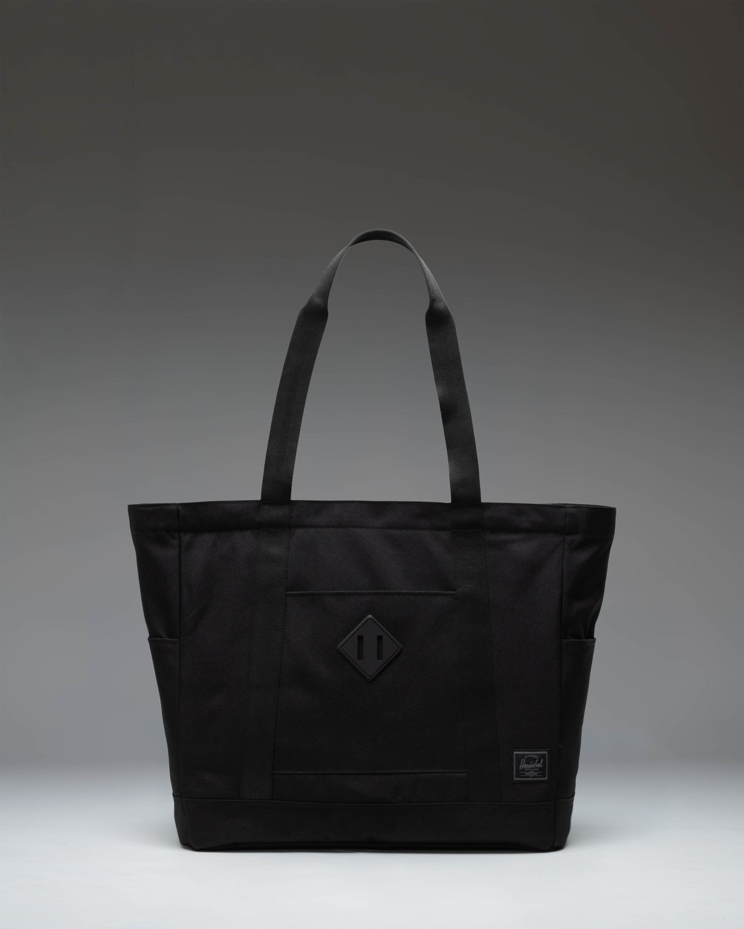 Herschel Heritage Tote in Black Tonal, featuring a clean front view with dual top carrying handles and the classic Herschel logo label.