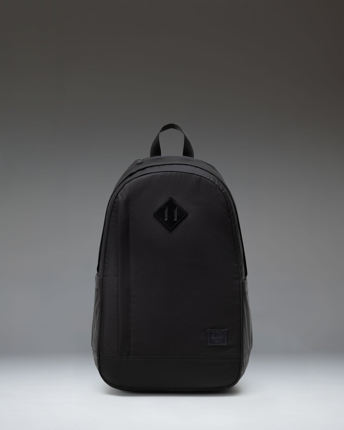 Herschel Seymour Backpack in black, showing the front view with dual straps, a front zippered pocket, and the classic Herschel woven label.