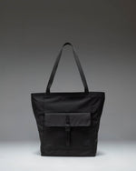 Herschel Retreat Tote bag in black, showcasing its clean design, dual carrying handles, and classic woven label on the front.