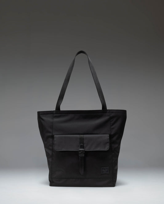Herschel Retreat Tote bag in black, showcasing its clean design, dual carrying handles, and classic woven label on the front.