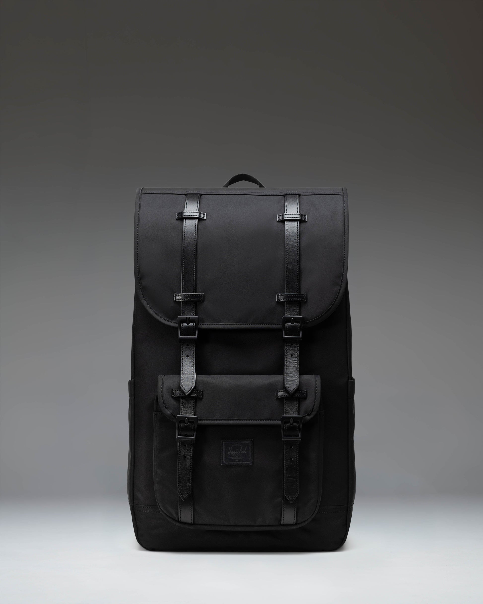 Black Herschel Little America Backpack featuring a classic mountaineering design with magnetic strap closures and a front pocket.