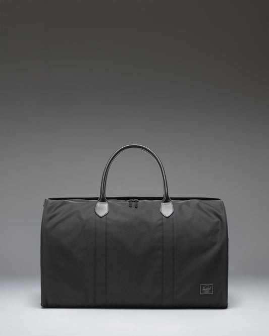 Herschel Novel Duffle bag in black, showing the clean classic design, durable handles, and signature shoe compartment.