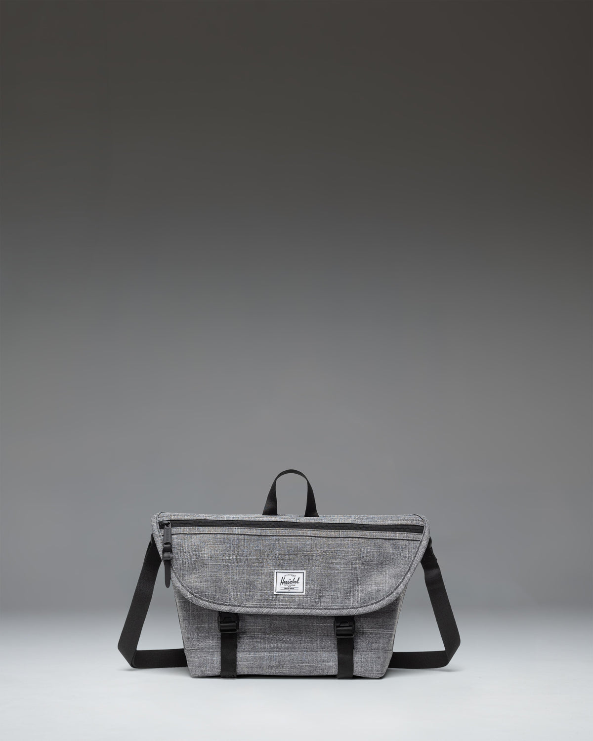 Herschel Supply Co. Cove Small Messenger bag in Raven Crosshatch grey, showing a front view with a flap closure, handle, and adjustable shoulder strap.