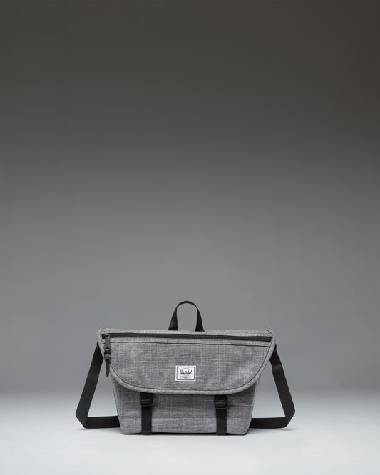 Herschel Supply Co. Cove Small Messenger bag in Raven Crosshatch grey, showing a front view with a flap closure, handle, and adjustable shoulder strap.