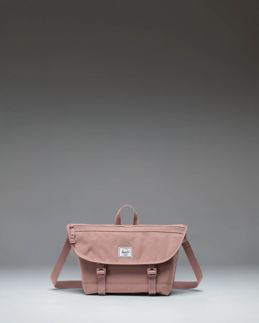 Herschel Supply Co Cove Small Messenger bag in Ash Rose pink, viewed from the front, showcasing its compact, structured design.