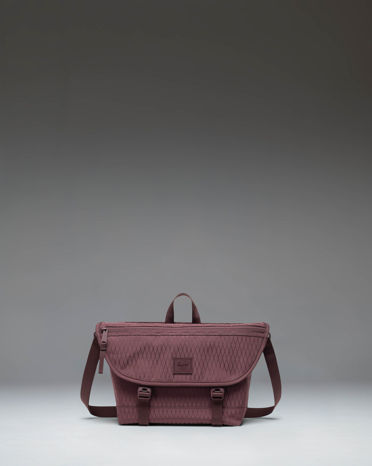 Herschel Supply Co. Cove Small Messenger bag in Huckleberry Diamond pattern, showing the compact crossbody design with front buckle closure.