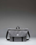 Herschel Supply Co. Cove Messenger bag in Raven Crosshatch grey, showing the front flap, buckle closure, and shoulder strap.