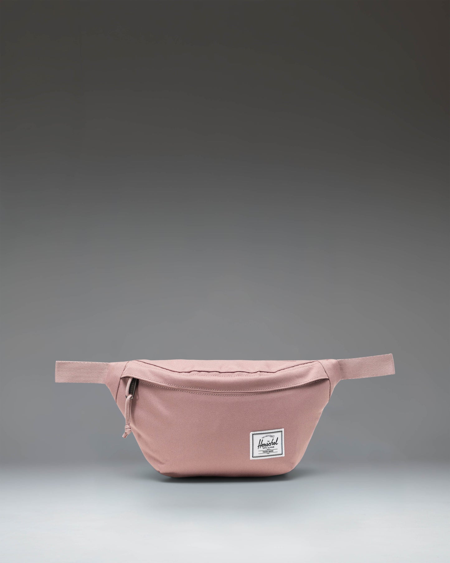 Herschel Classic Hip Pack in Ash Rose pink, featuring a front zippered pocket and an adjustable webbed strap with a buckle closure.