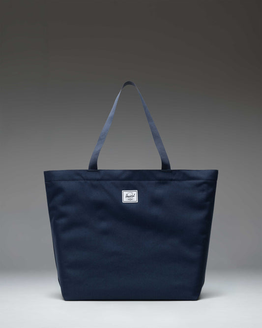 Herschel Classic Tote bag in navy blue, showcasing its clean front design and durable dual carrying handles.