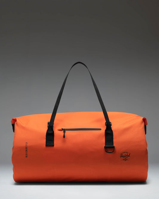 Herschel Supply Co. Dry Bag Duffle 55L in Vermillion Orange shown from a side view, featuring its waterproof design and durable carry straps.