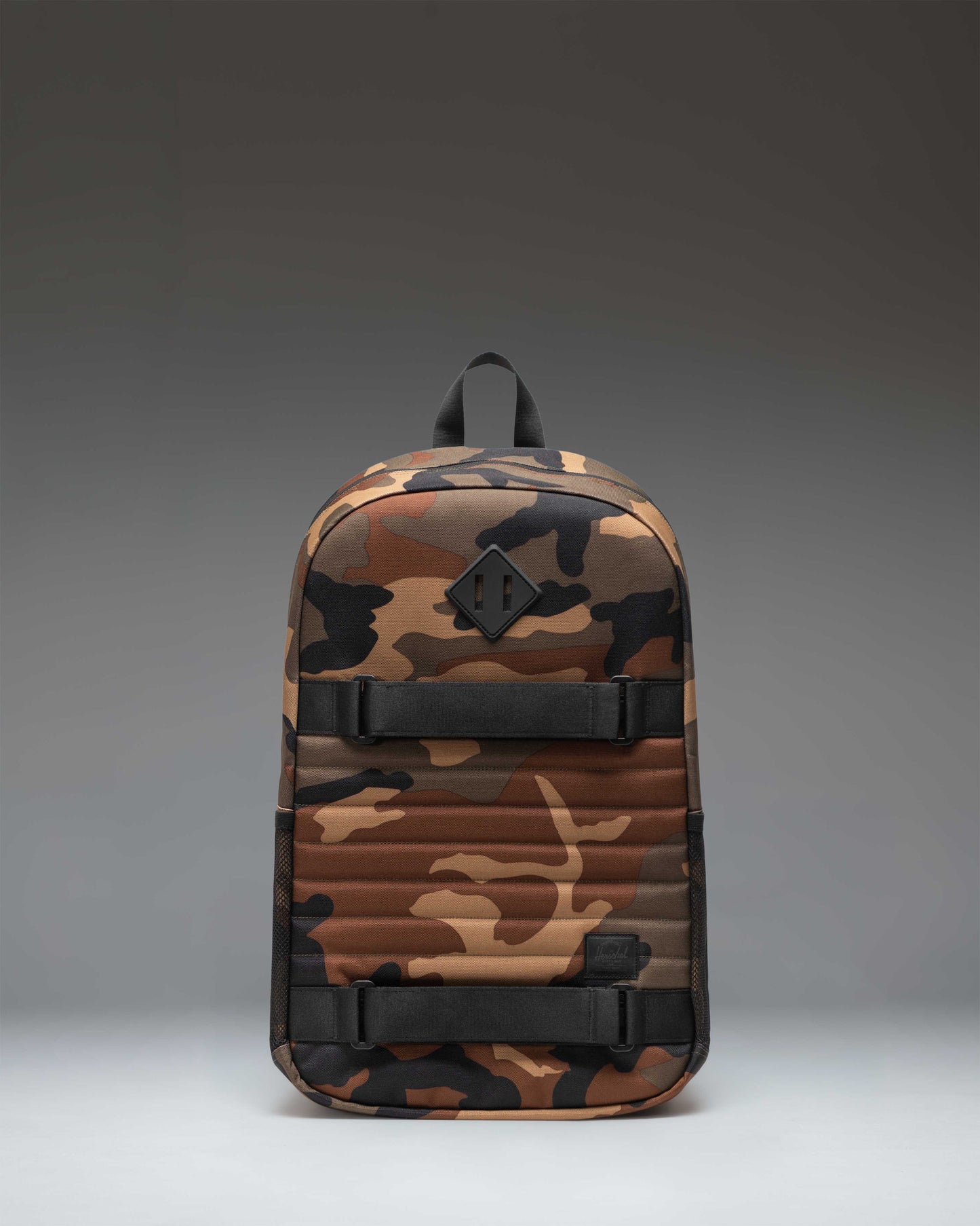 Herschel Supply Co. Fleet Skate Backpack in woodland camo and black, showing the front view with skate straps.