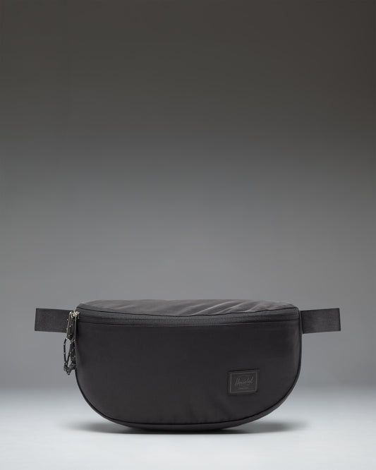 Herschel Supply Co. Kaine Hip Pack in black, featuring a front zippered pocket and an adjustable strap with a buckle.