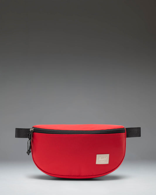 Herschel Supply Co Kaine Hip Pack in Barbados Cherry red, featuring a front zippered pocket and adjustable strap.