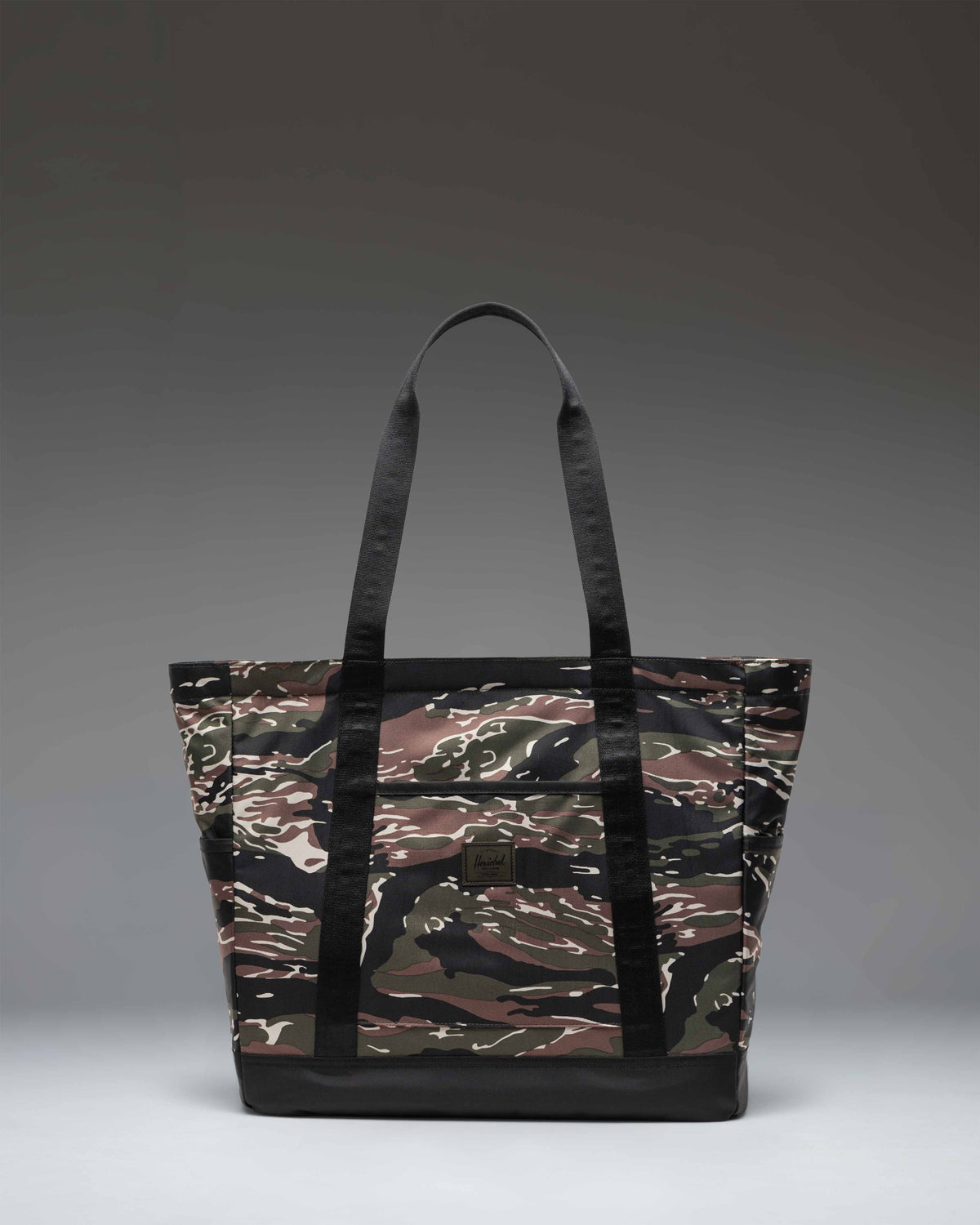 Herschel Heritage Tote in Tiger Camo pattern, showing a front view of the canvas tote bag with a classic woven label.
