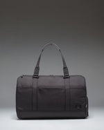 Herschel Novel Duffle Tech Cordura bag in black, showing a side view with durable handles and a clean, functional design for travel or gym use.