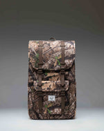 Herschel Little America Backpack in Realtree APX Camo featuring black straps and a front pocket.
