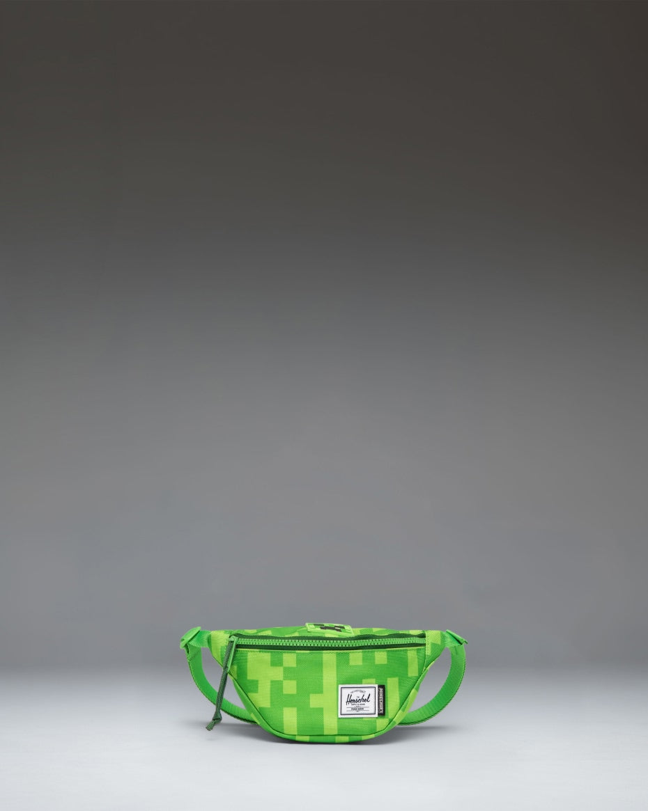 Minecraft Herschel Heritage Hip Pack Little Herschel in Creeper green pixelated pattern, featuring a black adjustable strap and buckle.