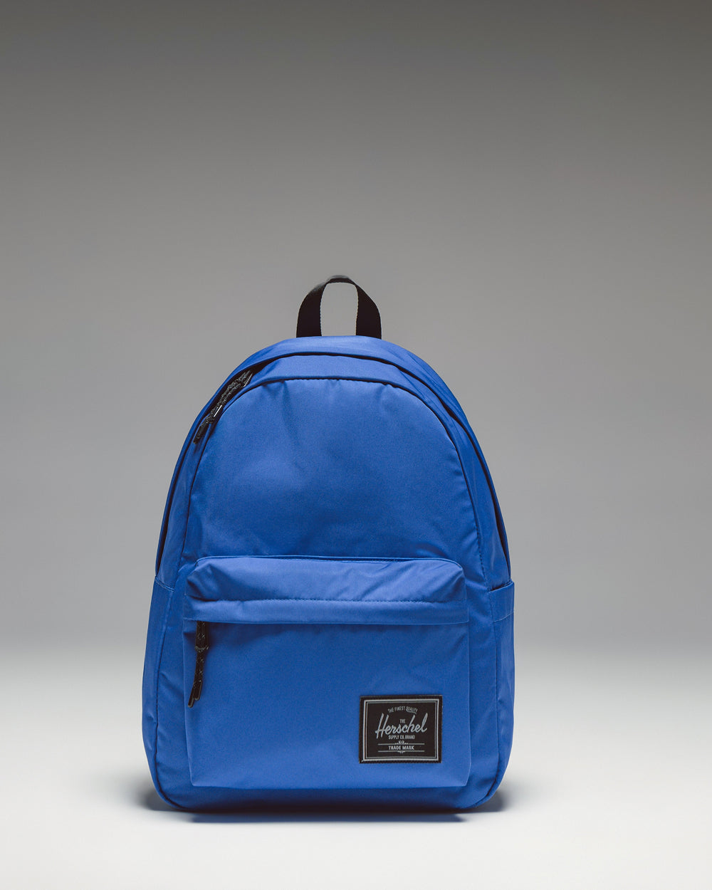 Herschel Supply Co. Classic Backpack Twill in Dazzling Blue, showcasing its clean design, front pocket, and classic woven label.
