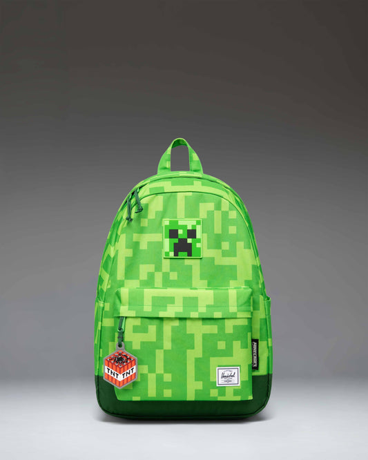 Herschel Supply Co. Minecraft Heritage Youth Backpack in pixelated green Creeper print, featuring a front storage pocket and diamond accent.